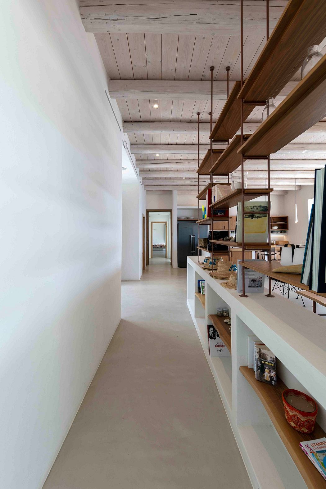 A cozy, modern interior with exposed wooden beams, built-in shelving, and minimalist decor.