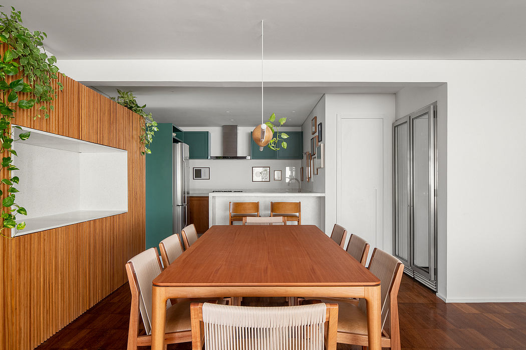 A modern kitchen and dining area with wood paneling, potted plants, and a large wooden table.