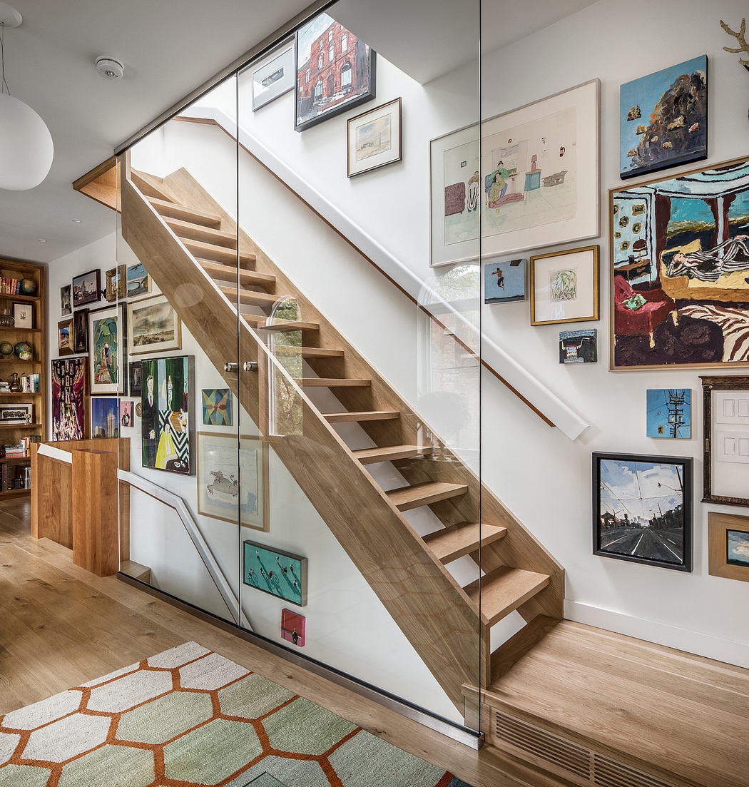 A modern, open staircase with wood treads flanked by glass walls, surrounded by eclectic art decor.