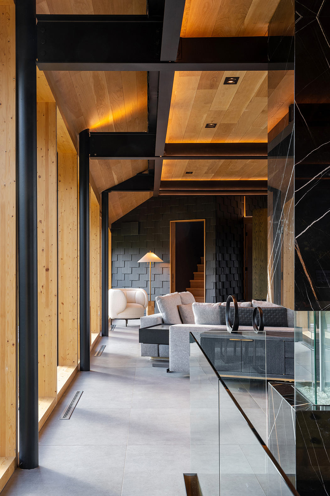 Modern, wooden-clad interior with sleek furniture, recessed lighting, and a glass-enclosed stairwell.
