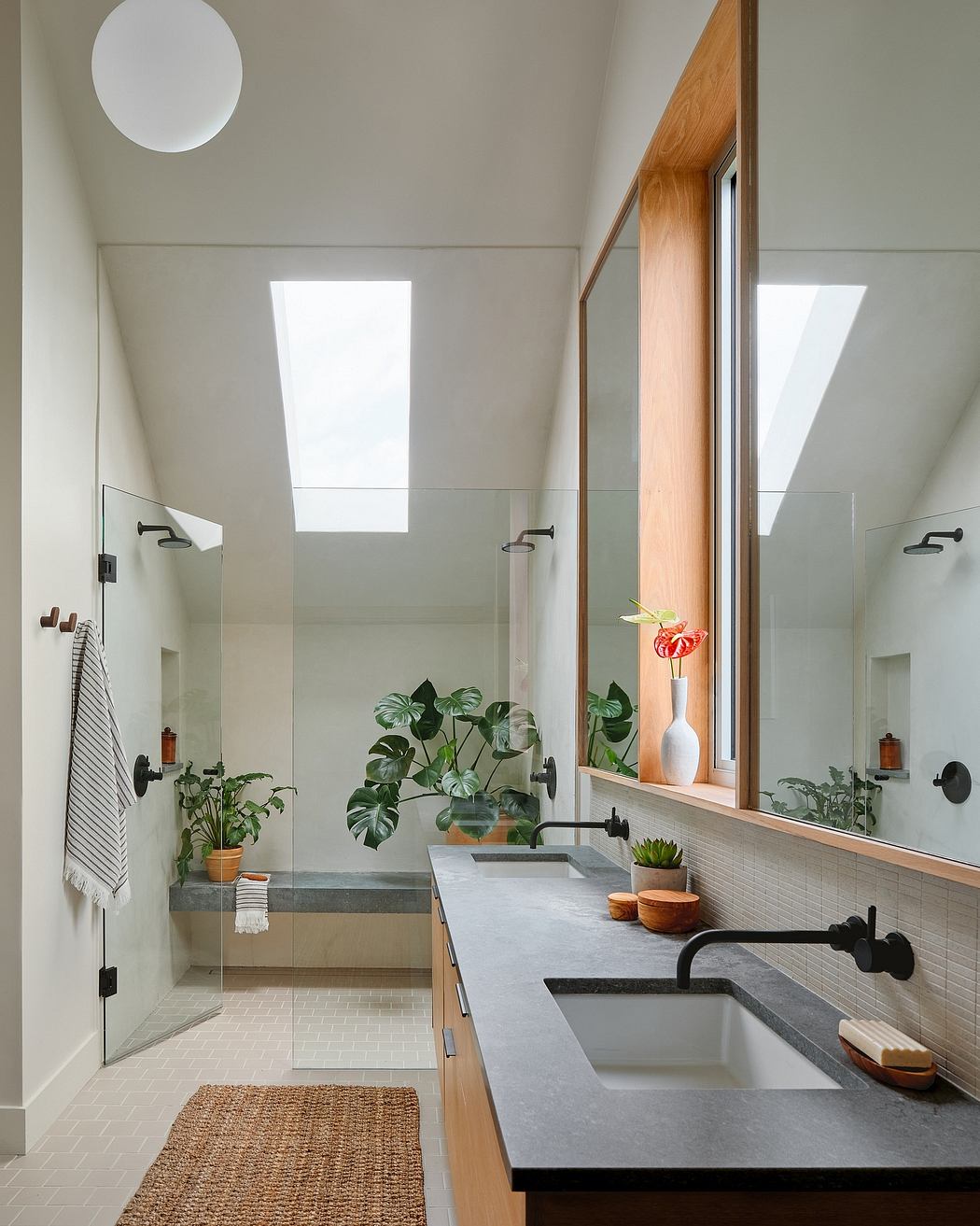 A minimalist, light-filled bathroom with wooden accents, lush plants, and a modern vanity.