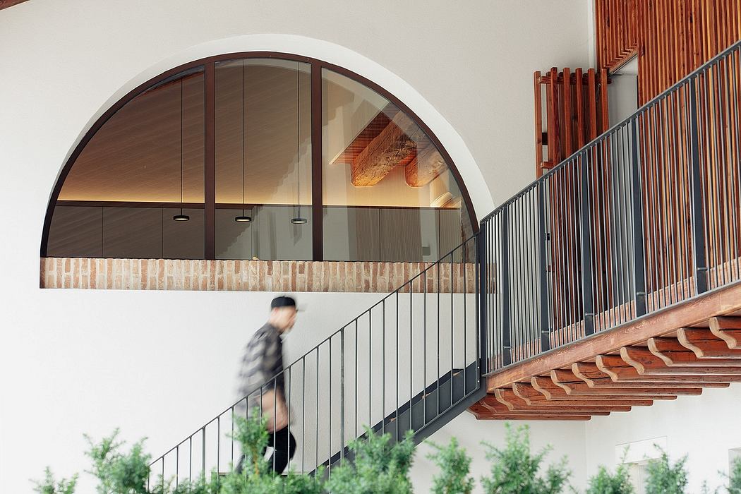 Arched window frames with wood detailing, concrete stairs and metal railings.