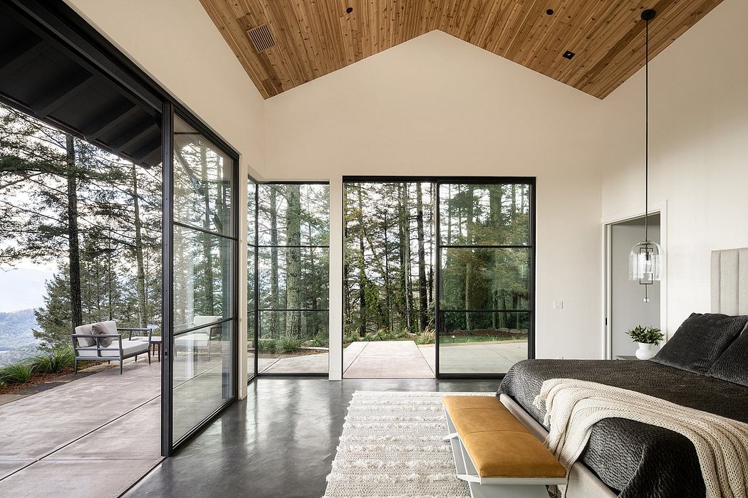Spacious modern bedroom with floor-to-ceiling windows overlooking a lush forest landscape.