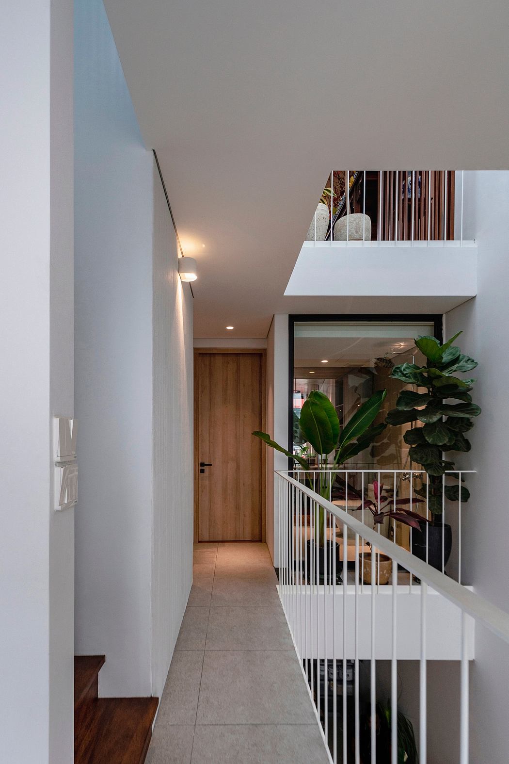 Sleek modern home interior with wooden accents, white open staircase, and lush greenery.