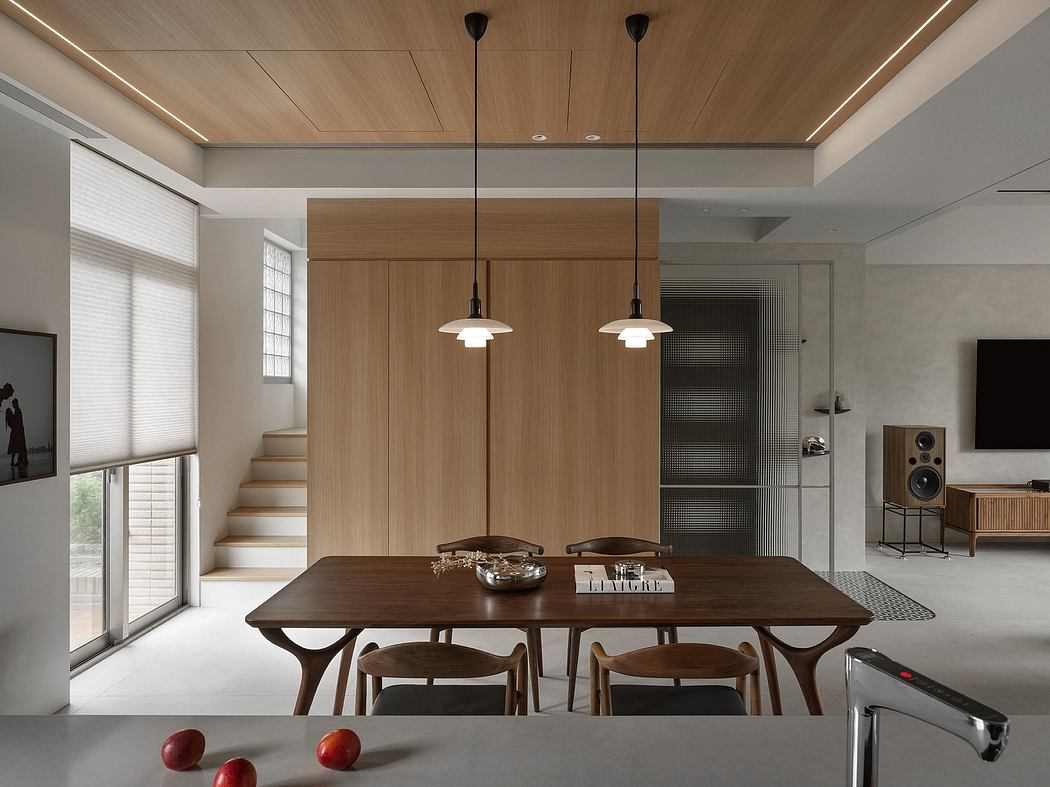 A modern, minimalist dining area with a wooden table, pendant lights, and built-in storage.
