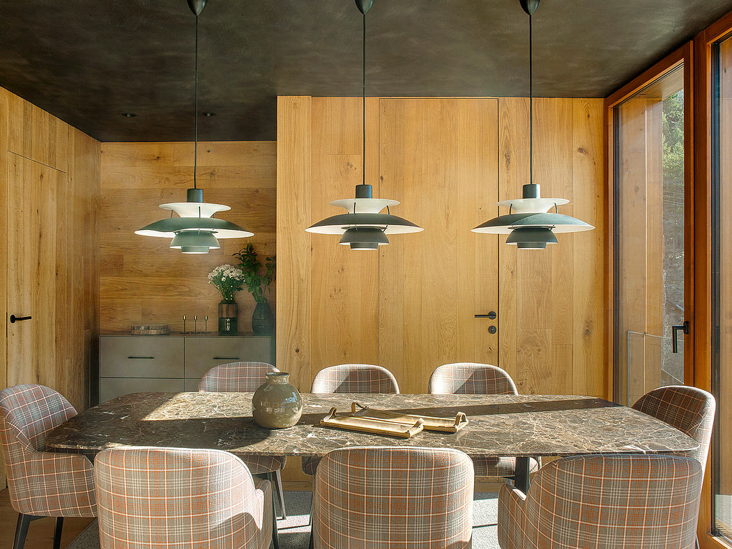 Rustic dining room with wooden walls, pendant lighting, and a large marble-topped table.