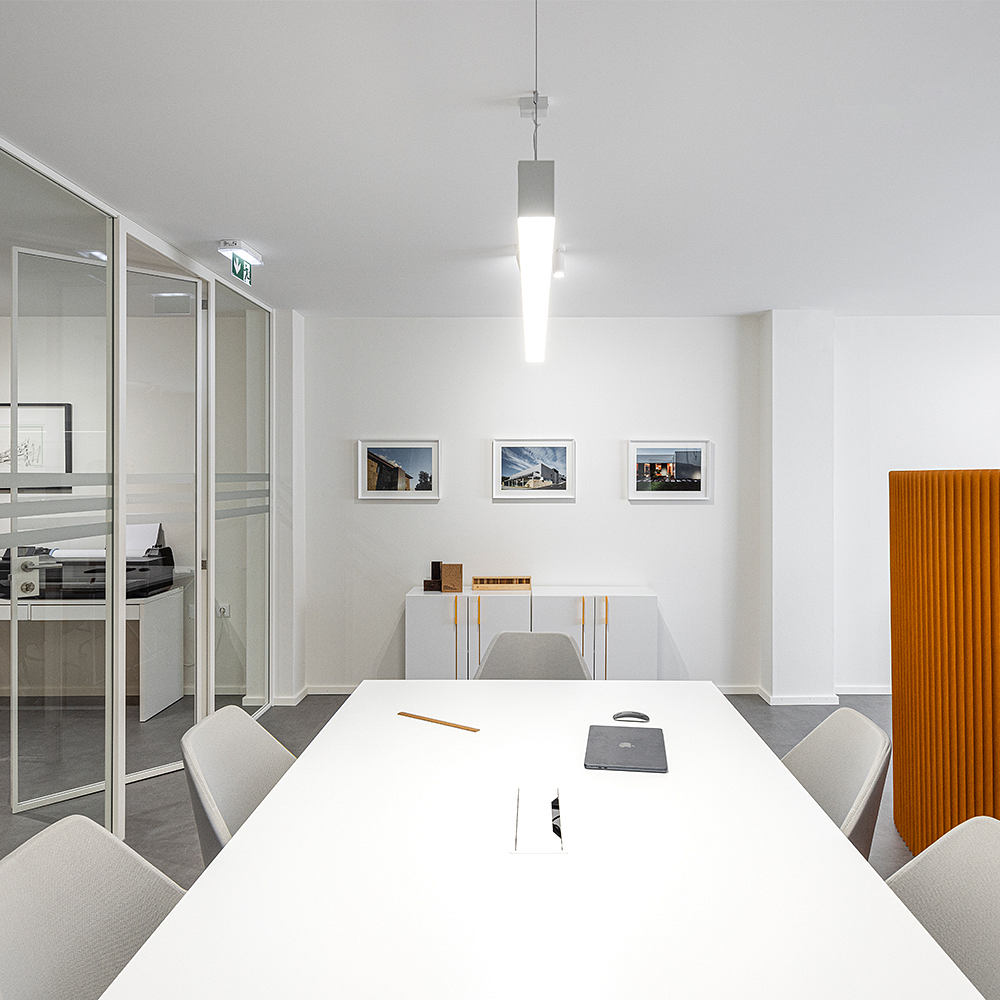 A modern, minimalist office space with sleek white furniture and warm lighting accents.