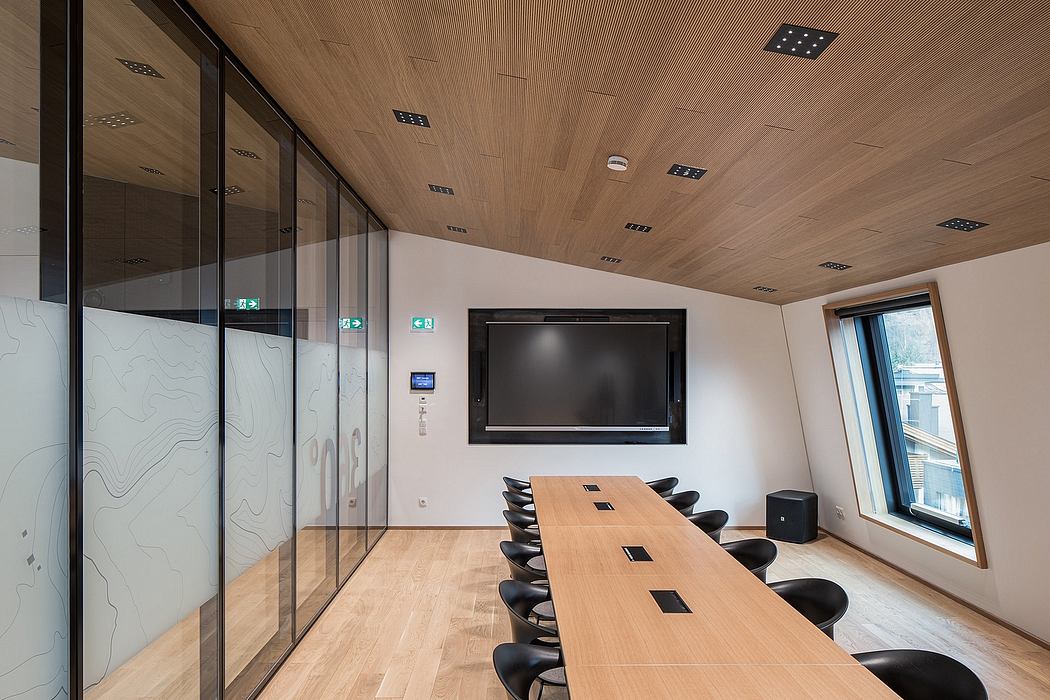 Modern meeting room with wood paneled ceiling, large display, and sleek conference table.