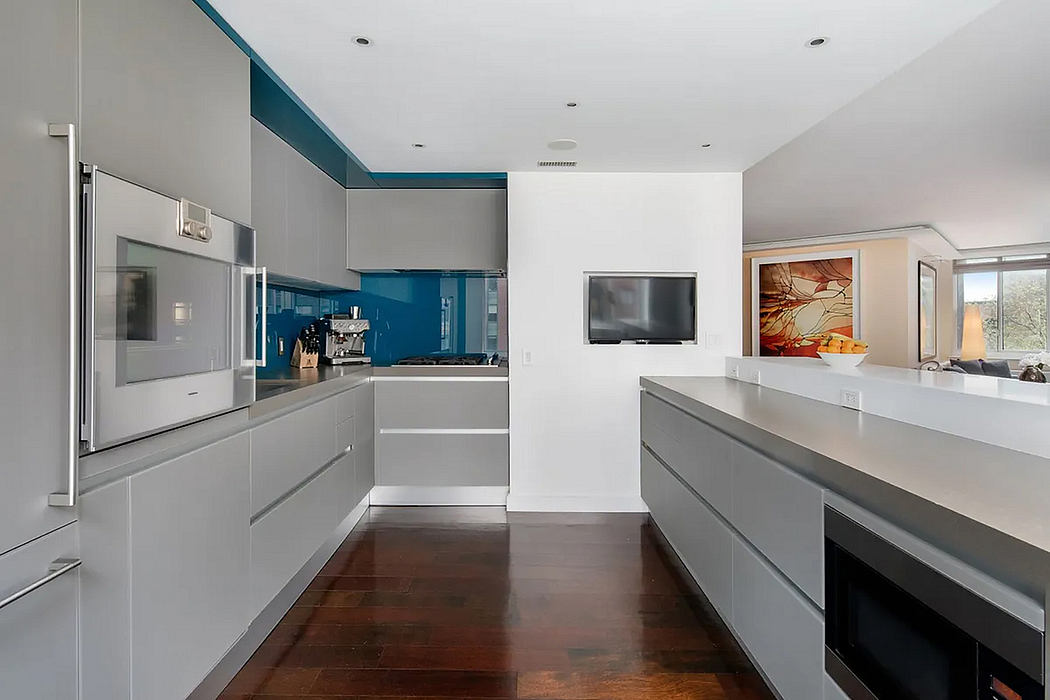 Modern kitchen featuring sleek gray cabinets, stainless steel appliances, and polished wood floors.