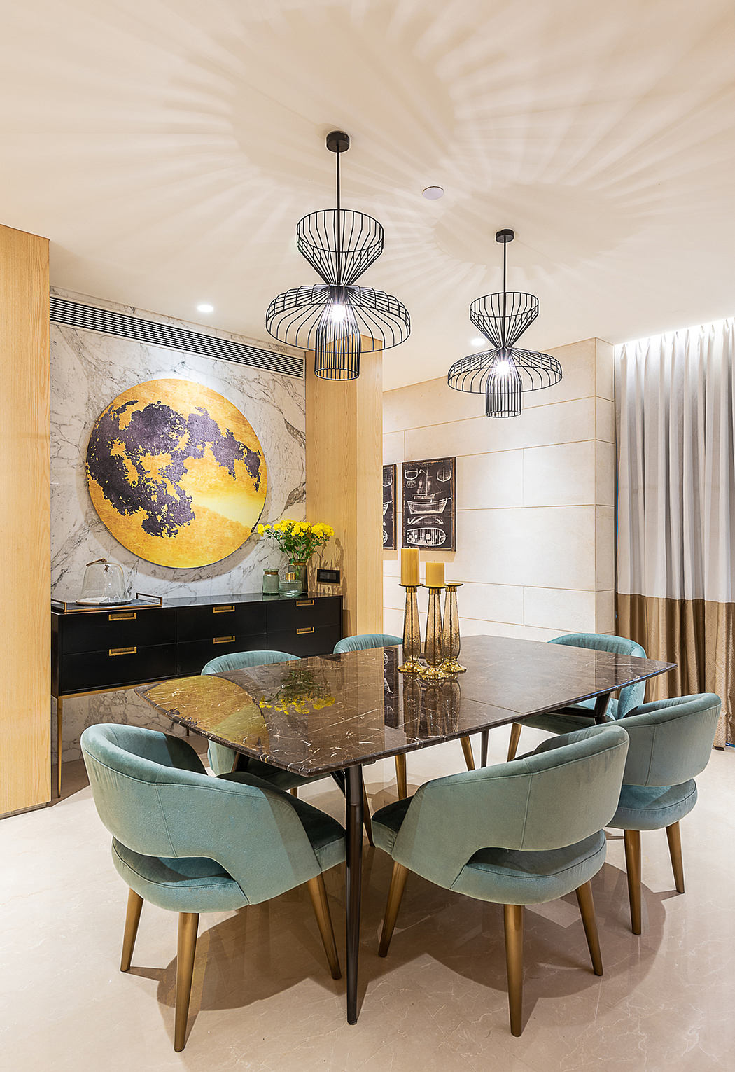 Stunning modern dining room with bold chandeliers, marble table, and teal velvet chairs.