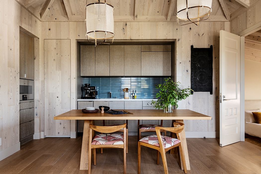 Rustic kitchen with wood-paneled walls, pendant lighting, and a large wooden dining table.