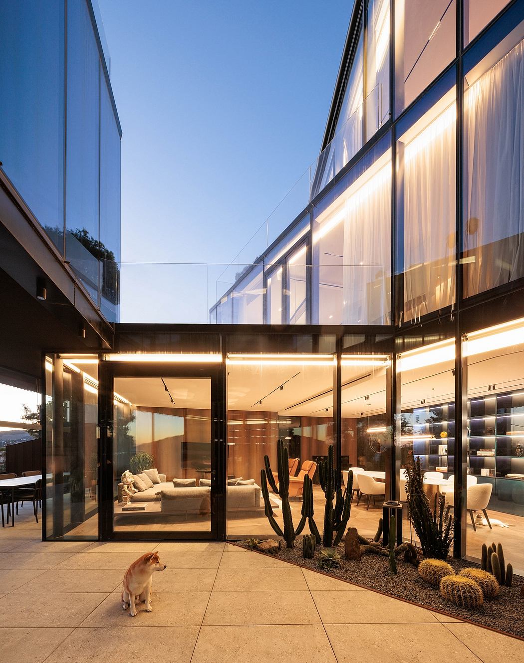 Stunning modern architectural design with sleek glass walls, warm lighting, and desert landscaping.