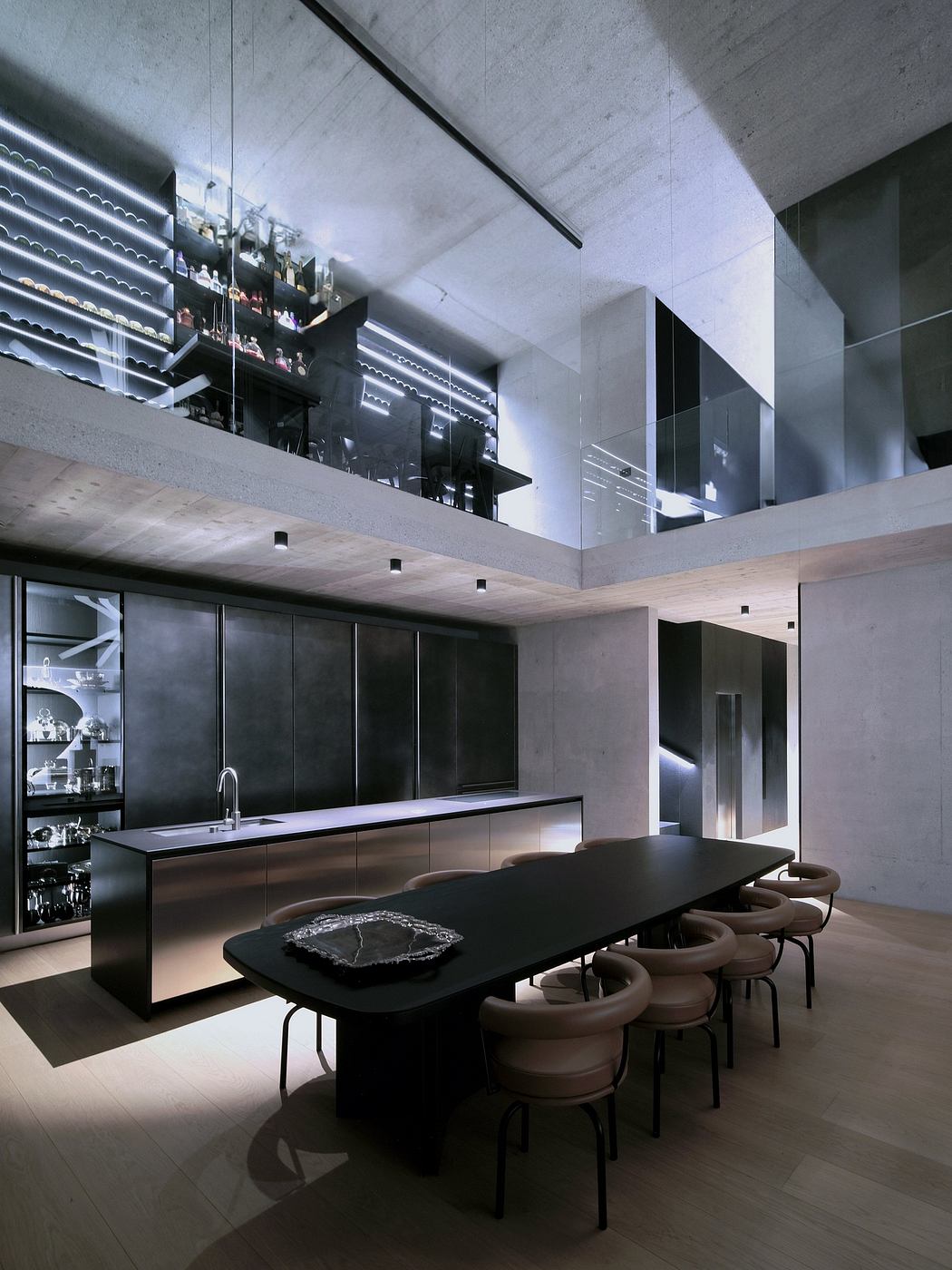 Sleek, modern kitchen with black cabinetry, a long dining table, and recessed lighting.