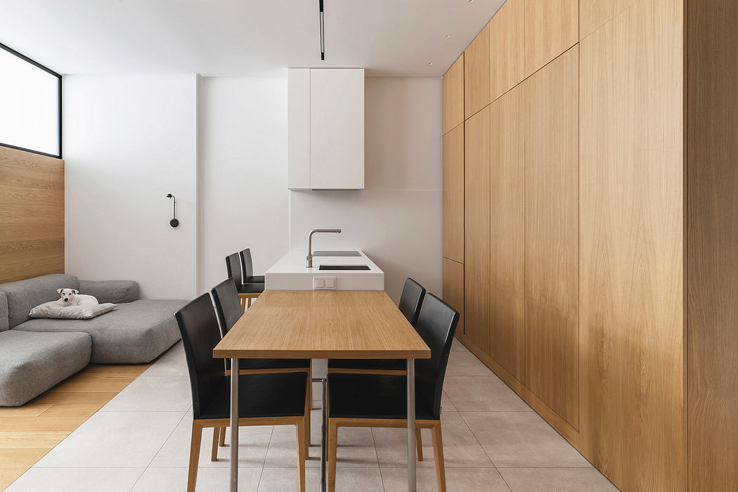 Clean, minimalist apartment interior with wooden walls, modern furniture, and open kitchen.