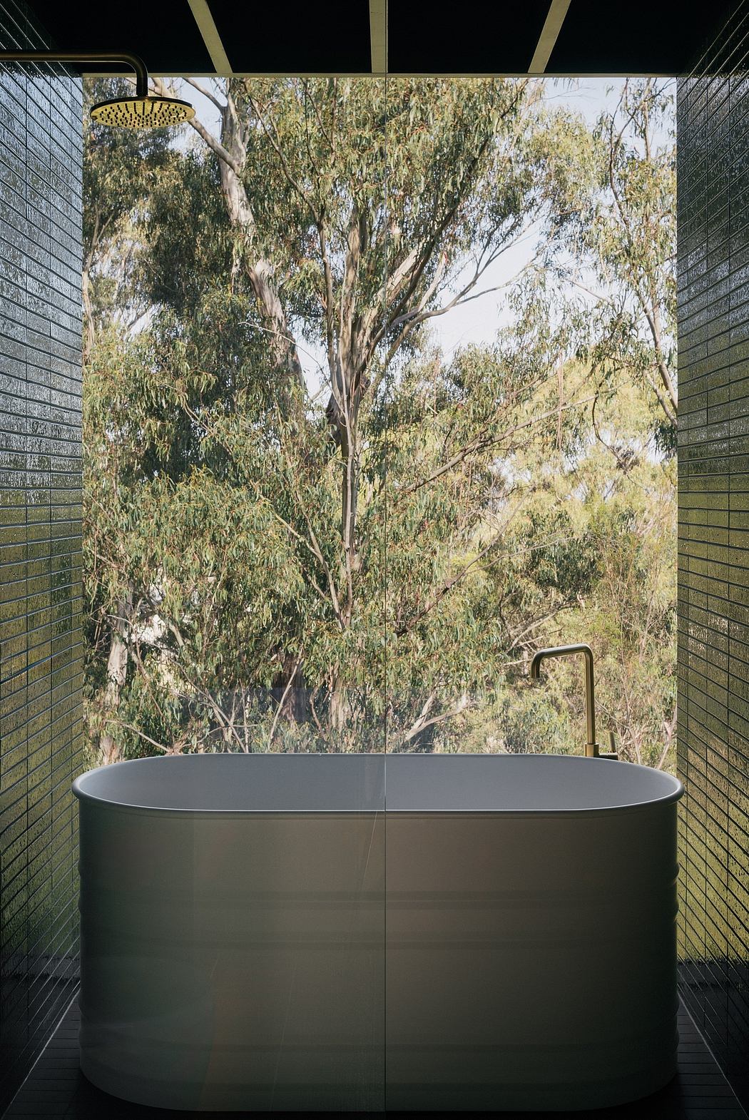 Modern bathroom with a minimalist gray bathtub against a scenic wooded backdrop.