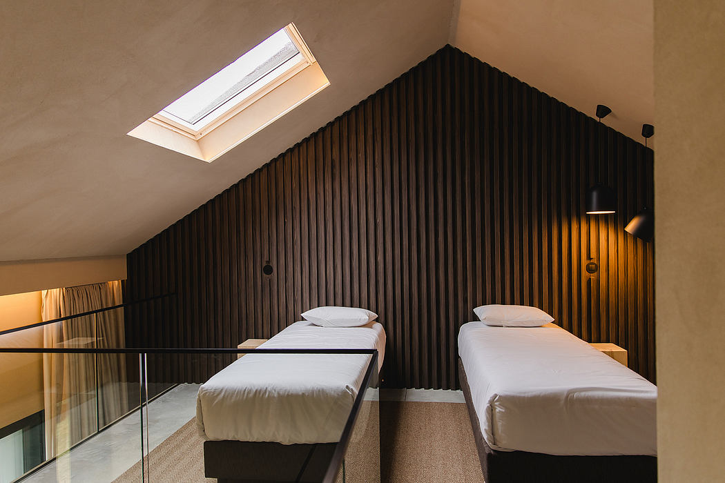 A cozy loft bedroom with a black wooden accent wall, skylights, and twin beds.