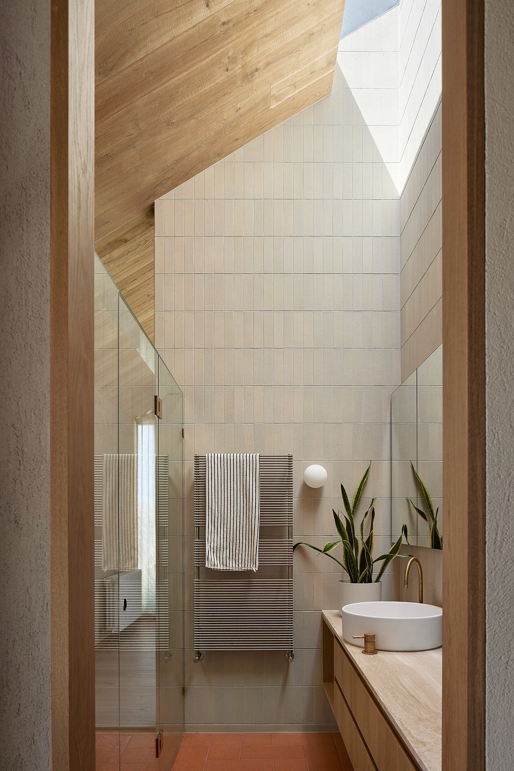 A modern bathroom with wood-panelled walls, white tiles, and a sleek vanity unit.