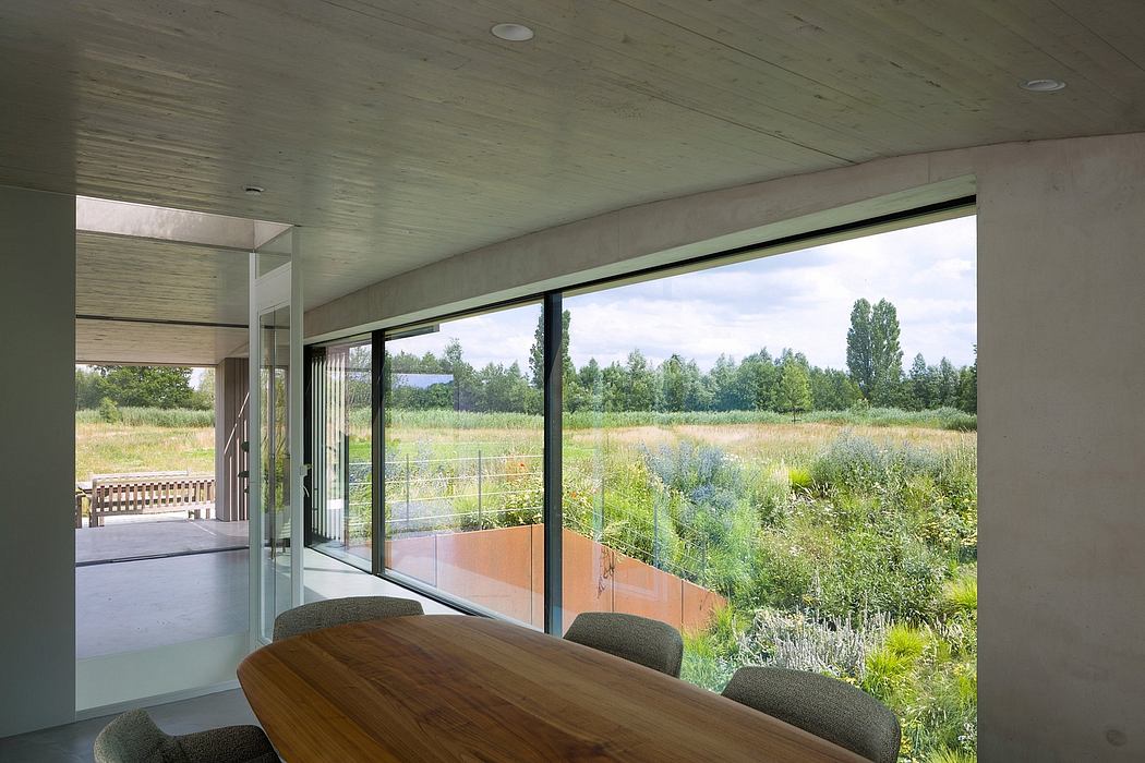 Minimalist interior design with expansive glass walls overlooking a lush outdoor landscape.