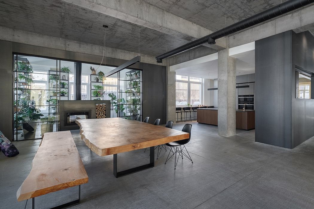 Spacious industrial-style dining area with a large wooden table, bench seating, and concrete walls.