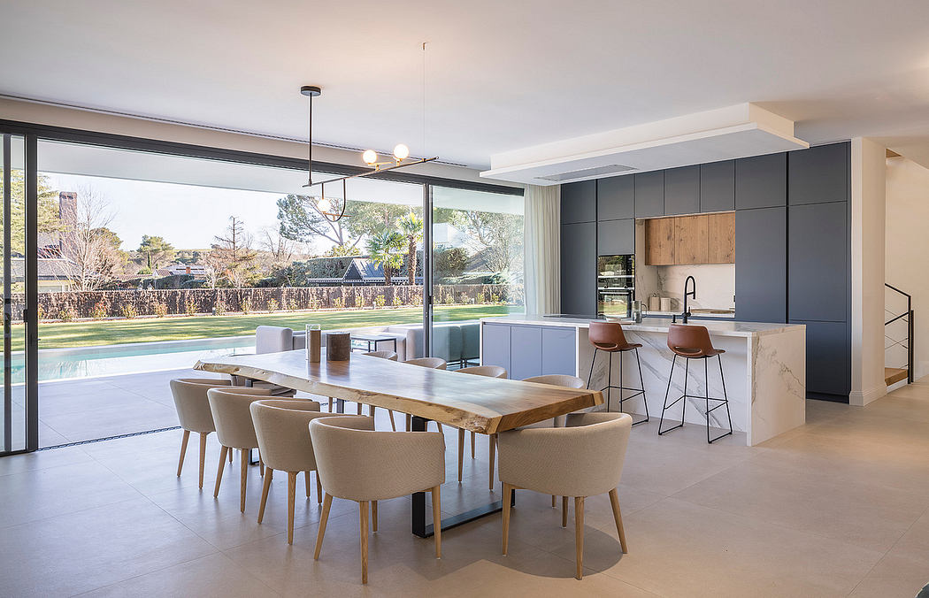 A modern, open-concept kitchen and dining area with sleek cabinets, natural wood, and expansive windows.