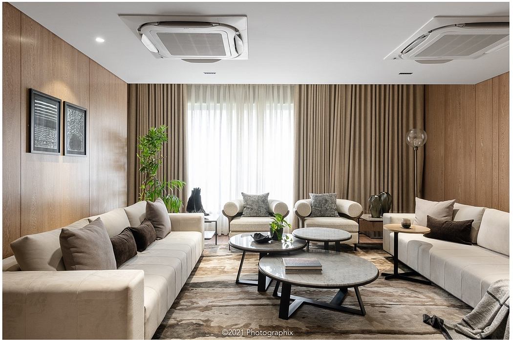 Spacious, modern living room with beige sofas, round coffee tables, and wood paneling.