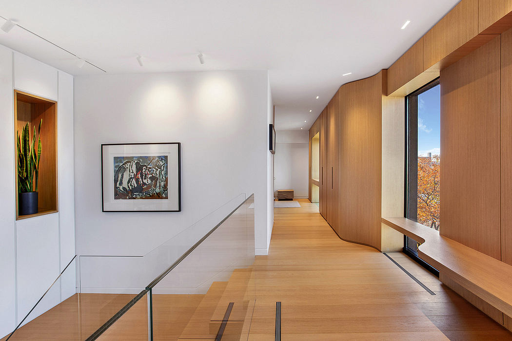 Sleek, modern hallway with wooden paneling, art display, and floor-to-ceiling windows.
