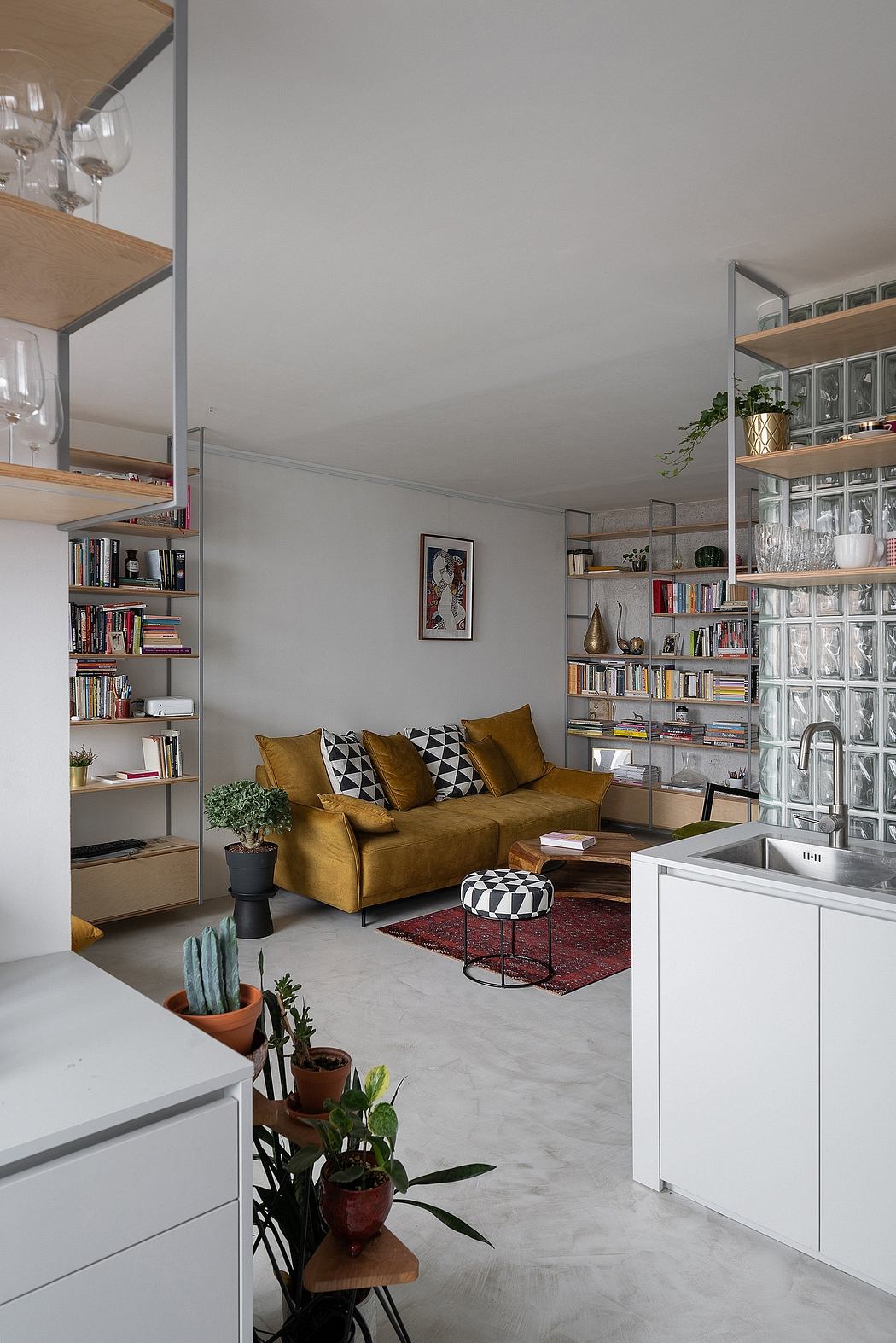 Cozy living room with mustard sofa, wooden shelves, and indoor plants; minimalist design.