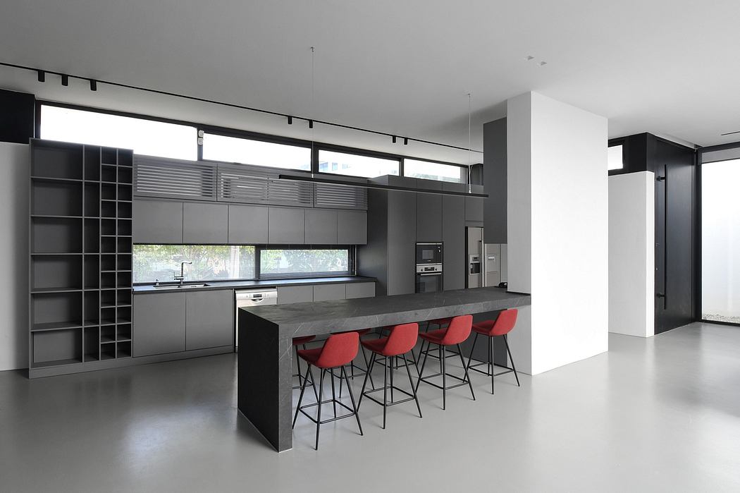 Sleek modern kitchen with minimalist black cabinetry, central island, and pop of red stools.