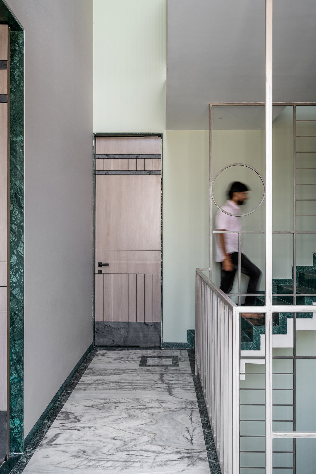 A modern interior with a marble-tiled floor, glass walls, and a wooden door.