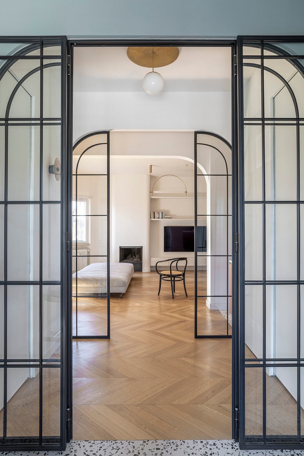 Elegant arched doorframes with black metal frames lead to a cozy, bright interior.