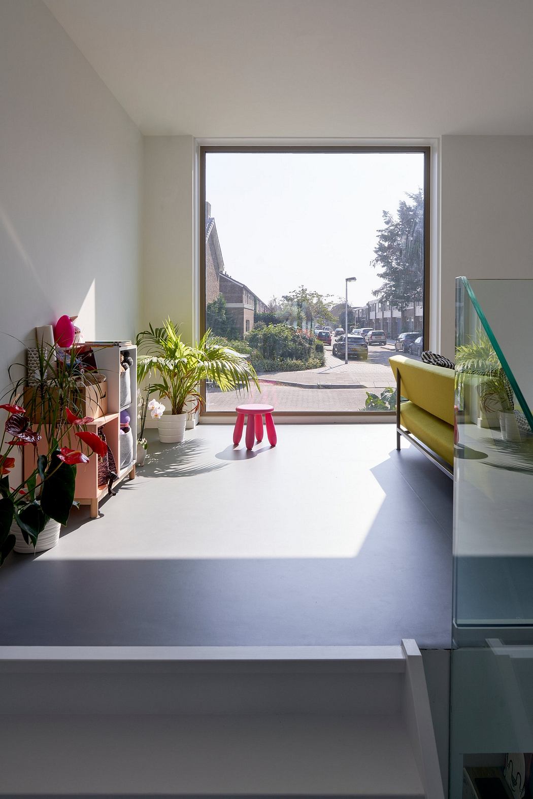 A modern, minimalist interior with large windows overlooking a lush, urban landscape.