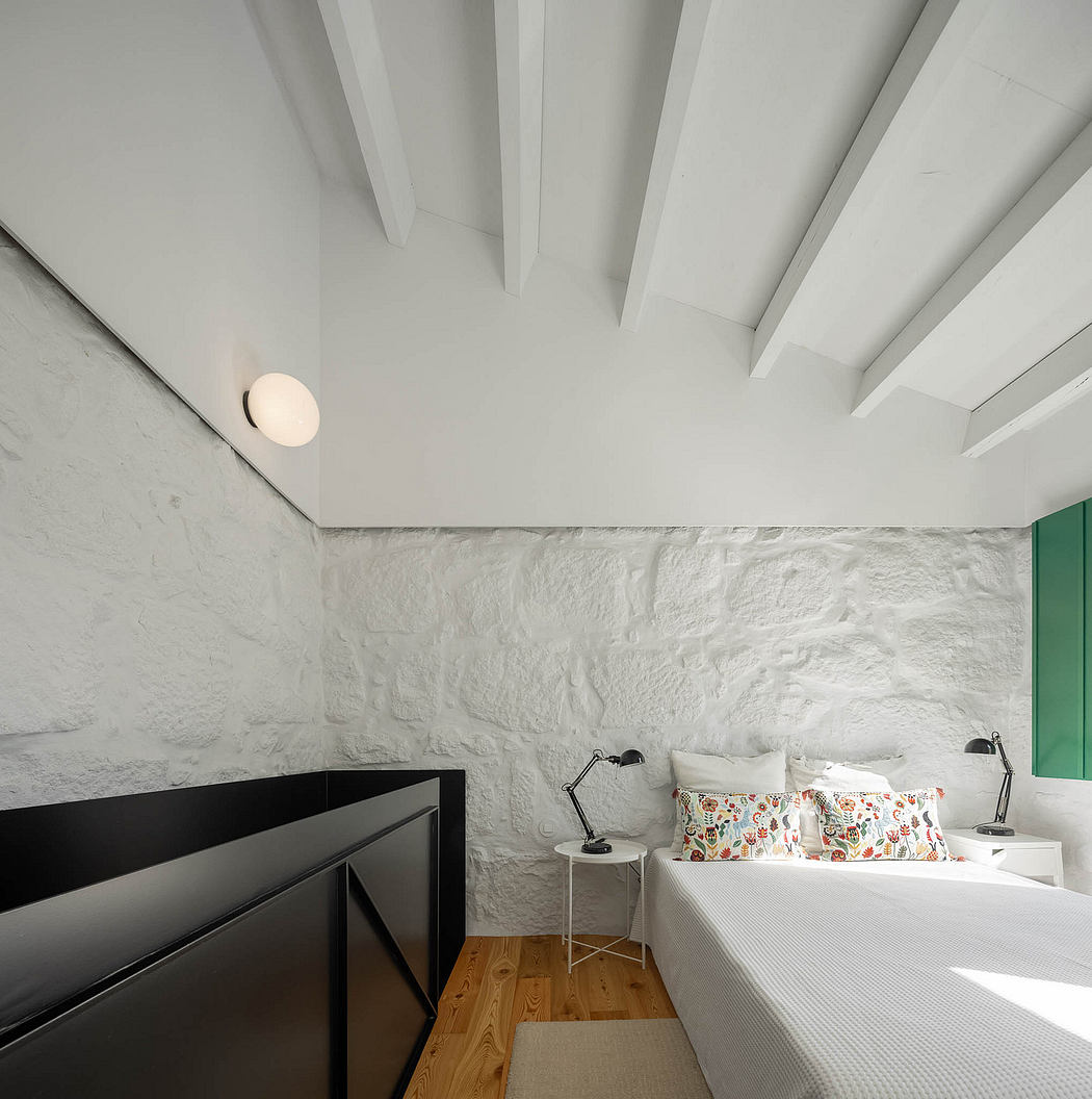Minimalist bedroom with white walls, wooden ceiling beams, and a geometric black cabinet.