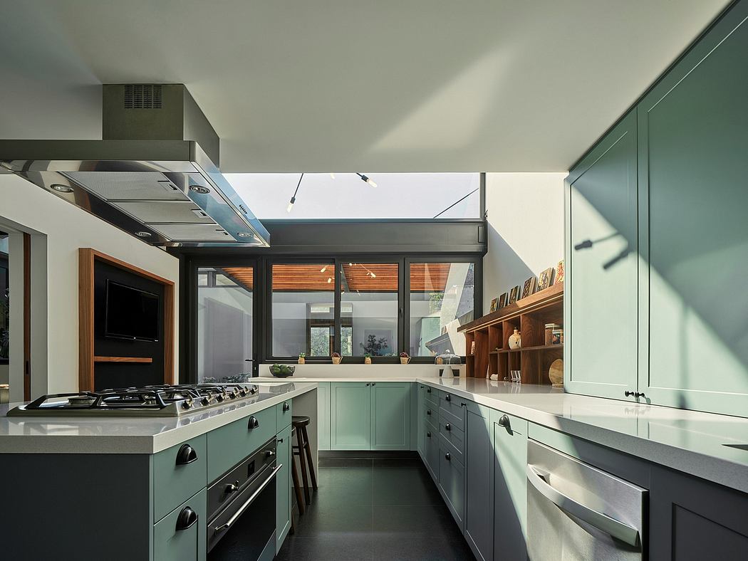 Modern kitchen with mint green cabinetry, steel appliances, and wood shelving.