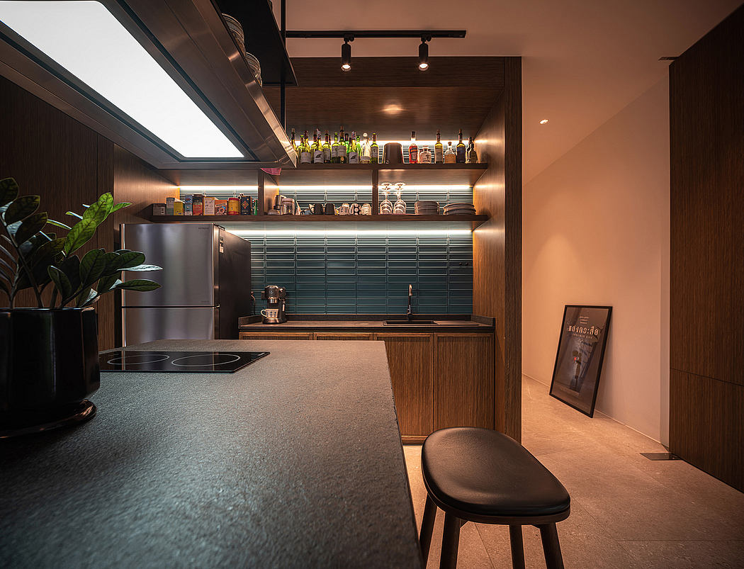 Well-lit modern kitchen with sleek black countertop, wooden cabinetry, and a variety of liquor bottles displayed on the shelves.