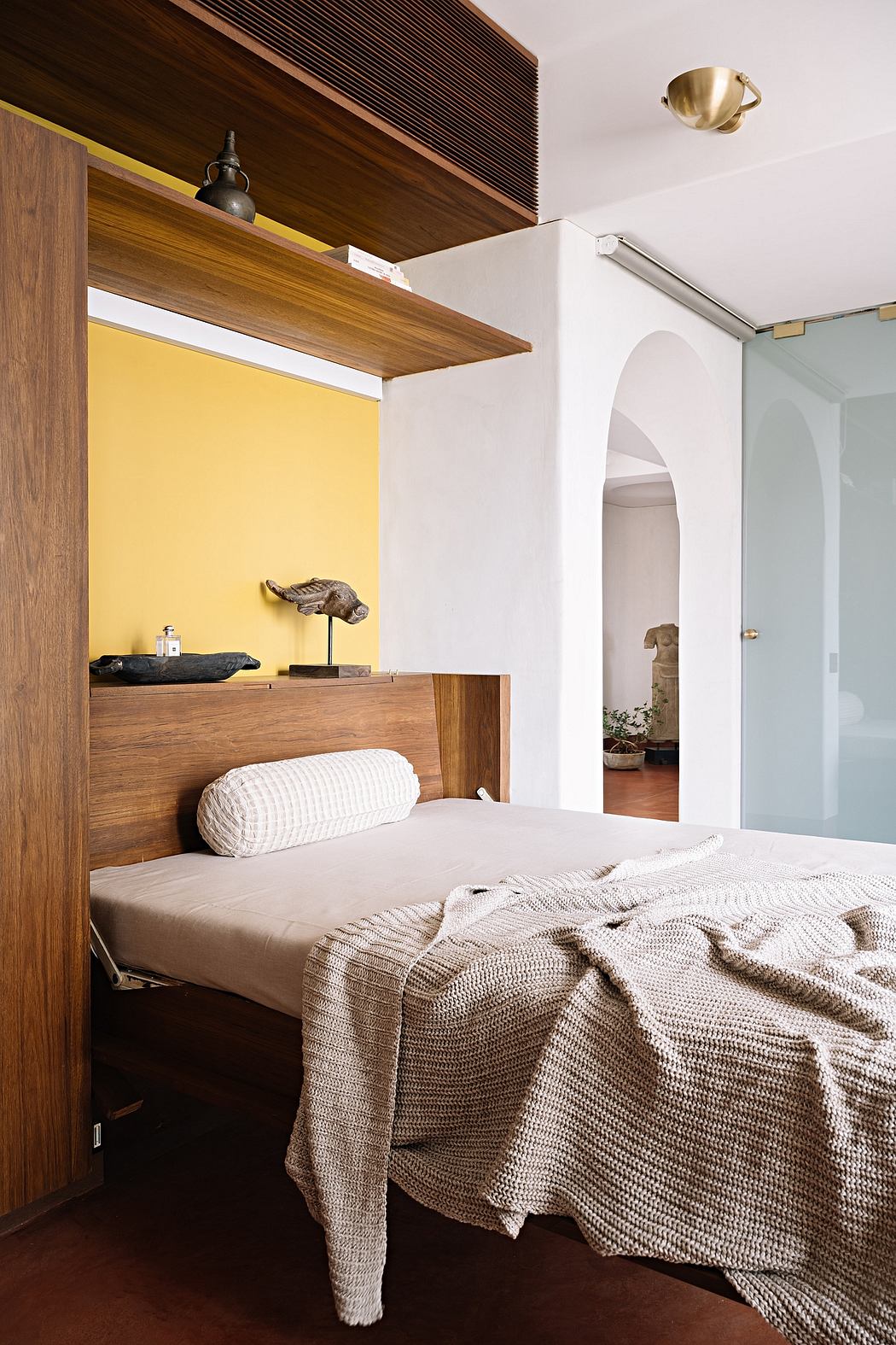 Cozy bedroom with warm wood tones, yellow accent wall, and textured bedding.