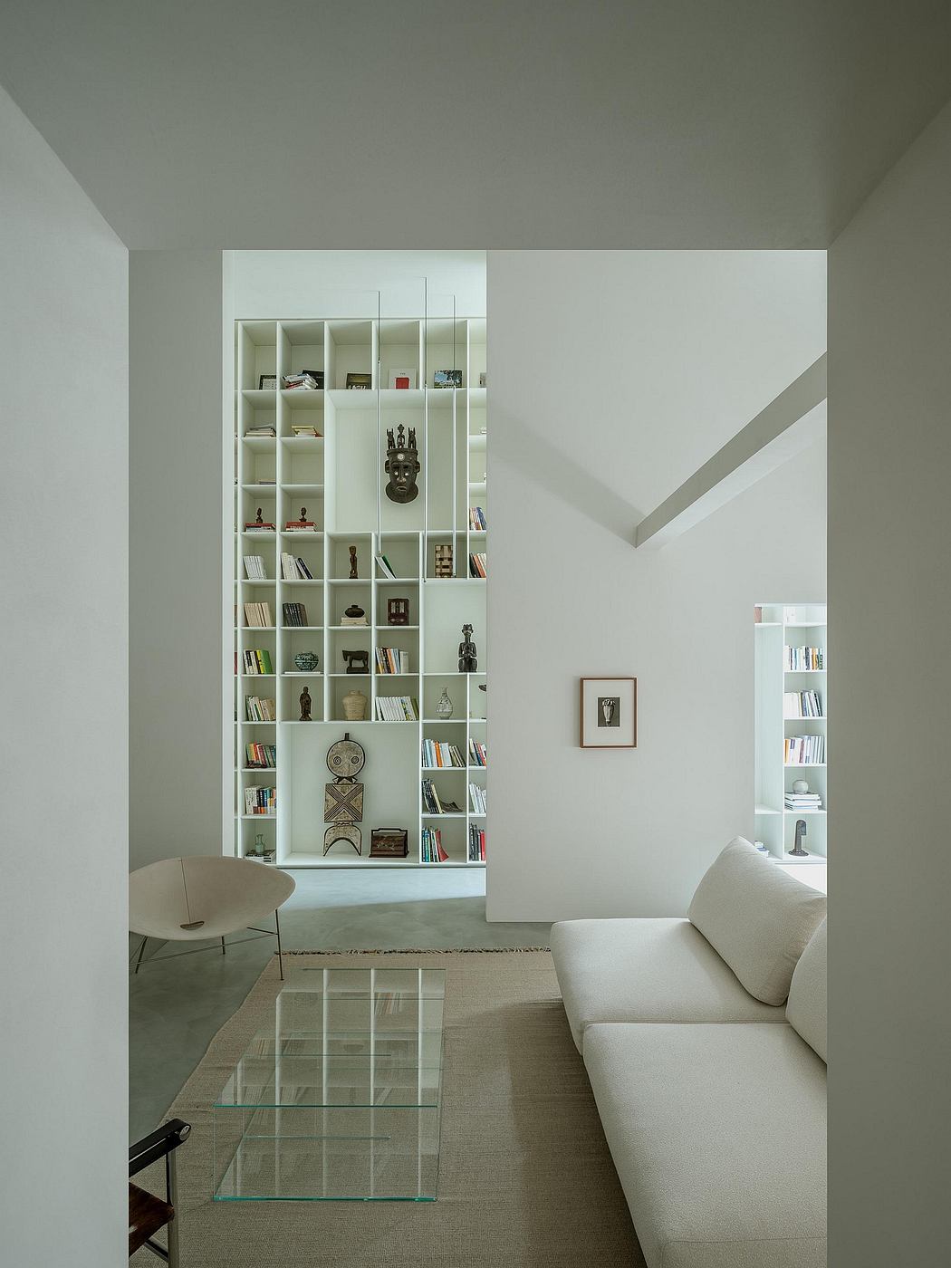 Minimalist living room with built-in bookshelves, modern furniture, and glass coffee table.