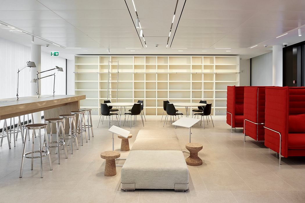Open office layout with modular shelving, seating, and lighting; red accents add a modern touch.