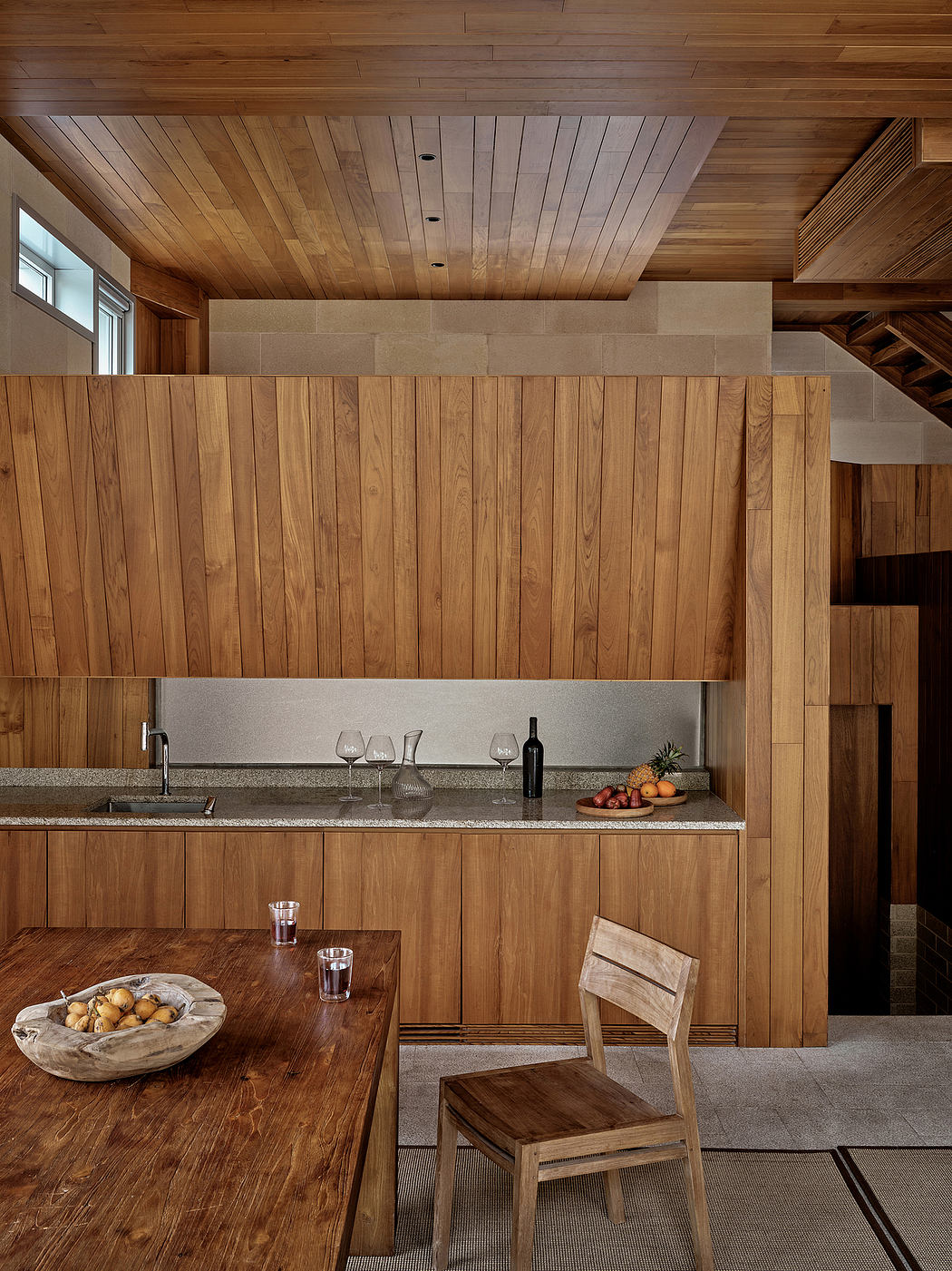 Rustic wooden interiors, with a sleek granite countertop and wine glasses, creating a cozy ambiance.