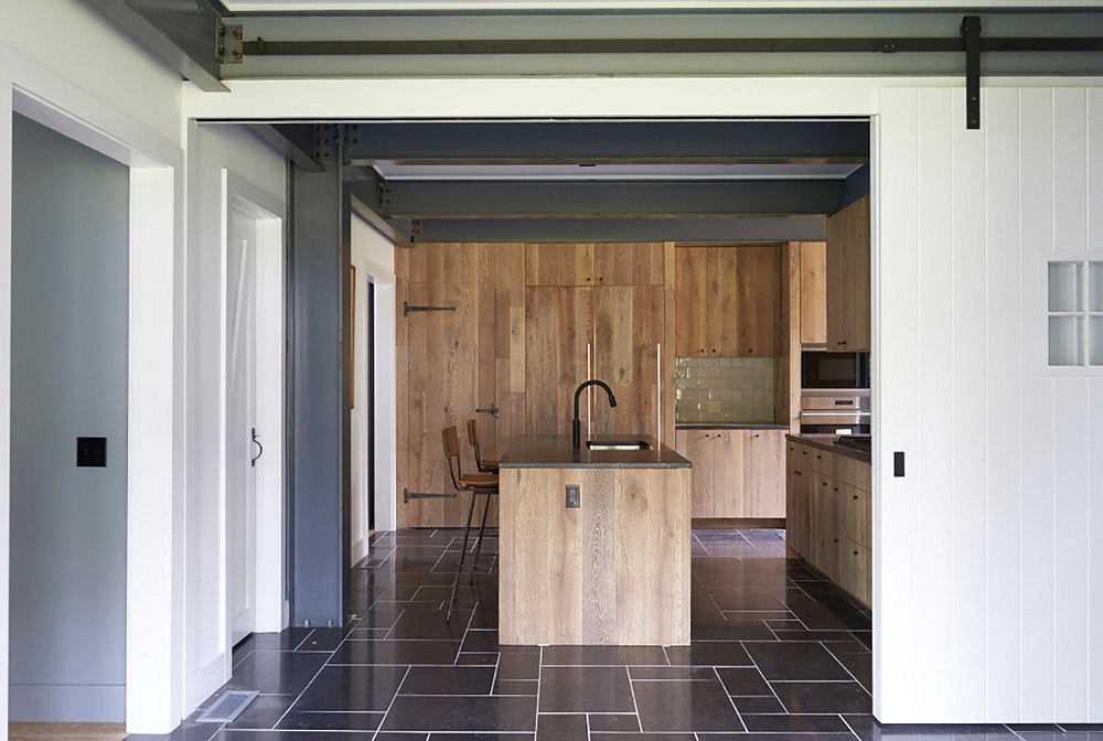 Modern kitchen with wood paneled walls, island, and dark tiled floor creating an industrial-rustic look.