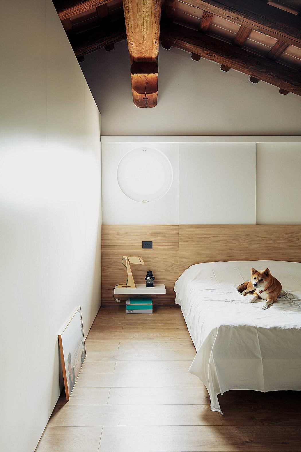Rustic wooden ceiling beams, minimalist decor, and a furry companion in the bedroom.