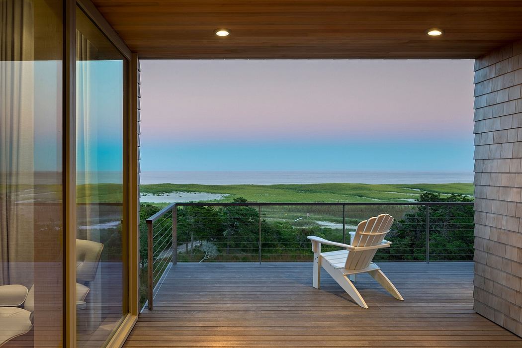 Expansive wooden deck offers panoramic views of lush green landscape and distant waters.