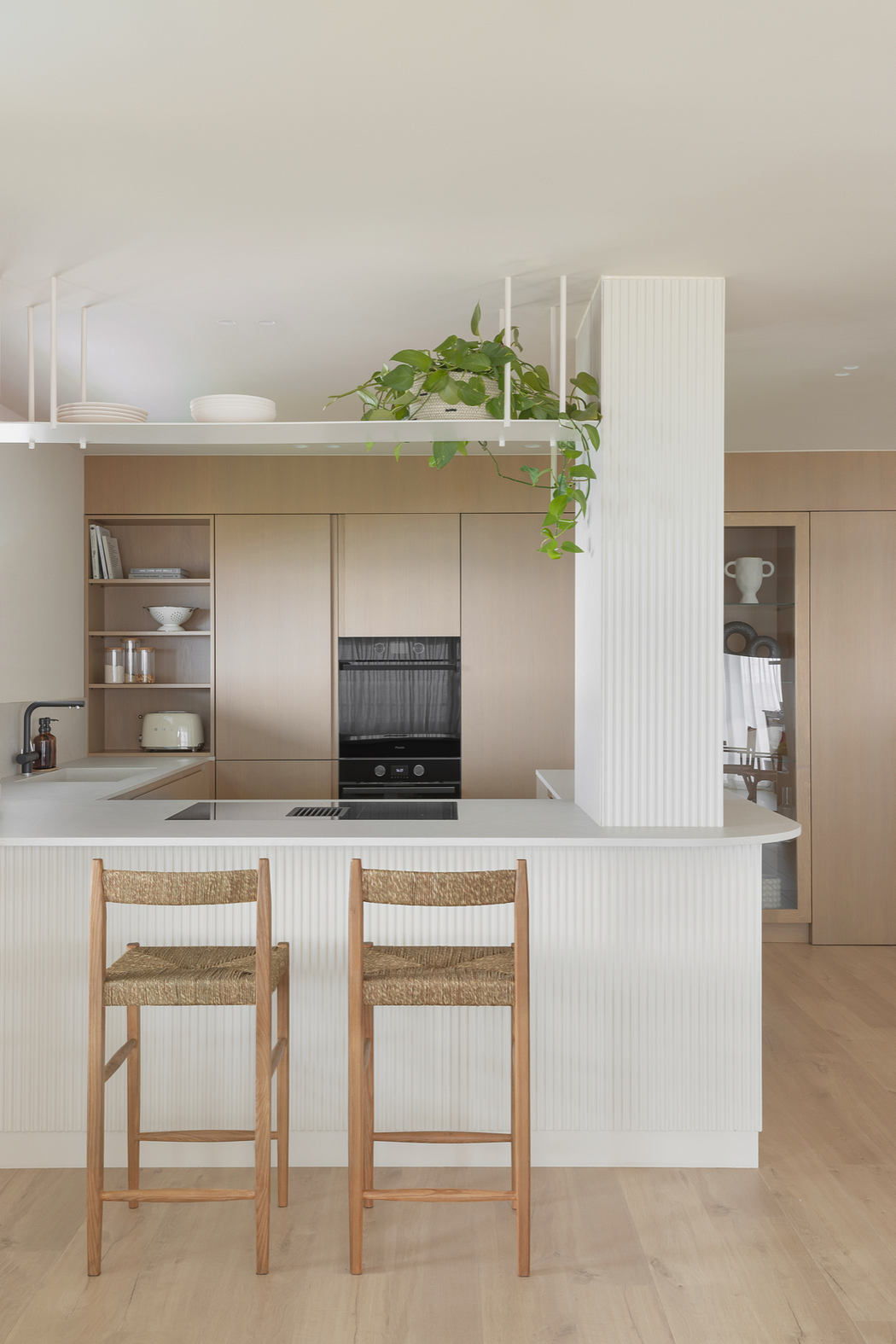 Contemporary kitchen with clean lines, light wood tones, and hanging plants.