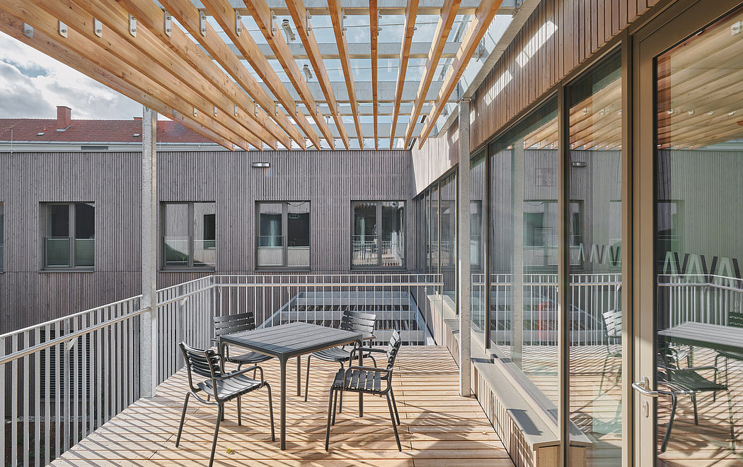 A modern, glass-enclosed courtyard with wooden beams and a deck with outdoor seating.