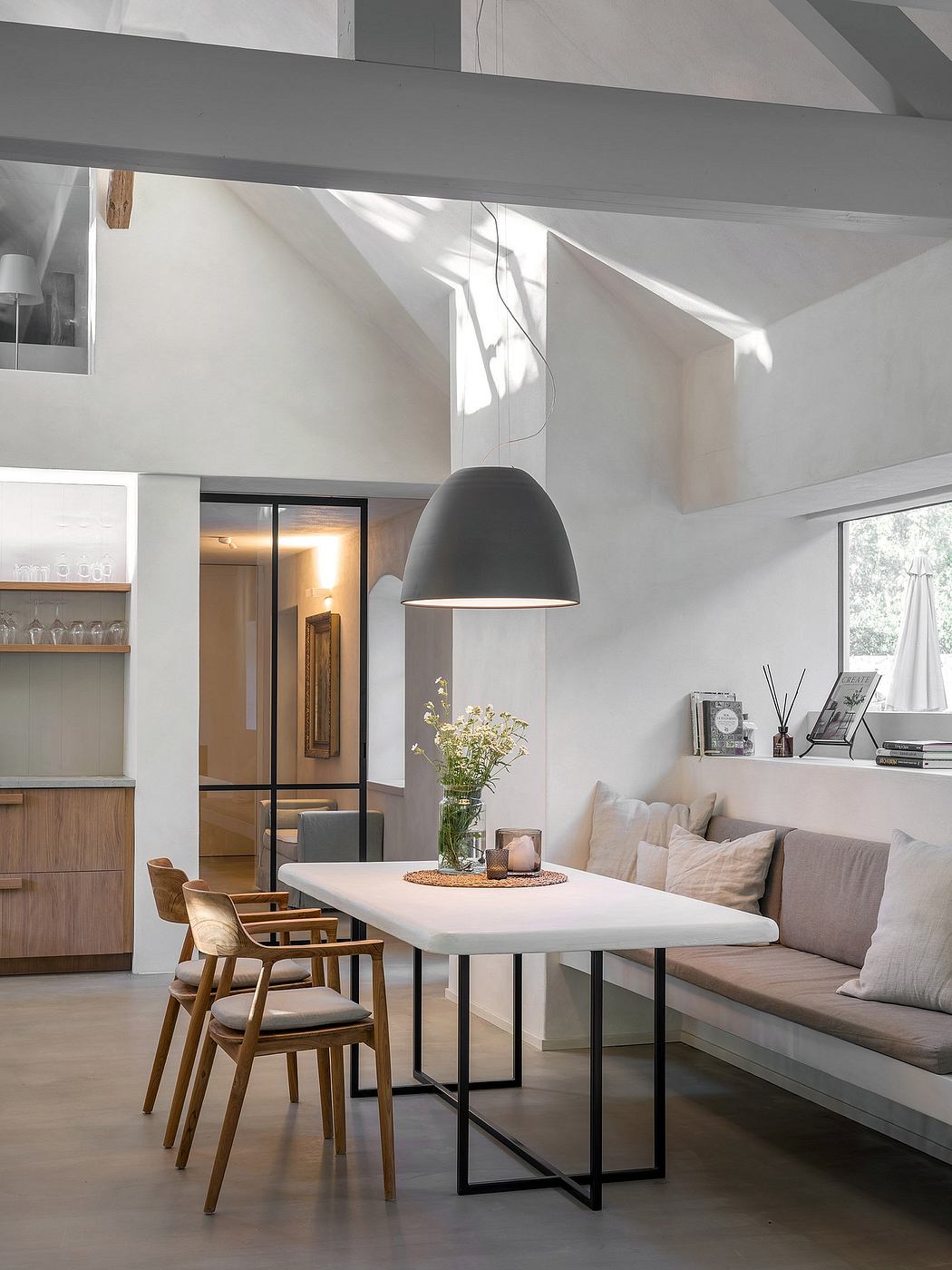 Modern, minimalist dining area with white table, pendant lamp, and wooden accents.