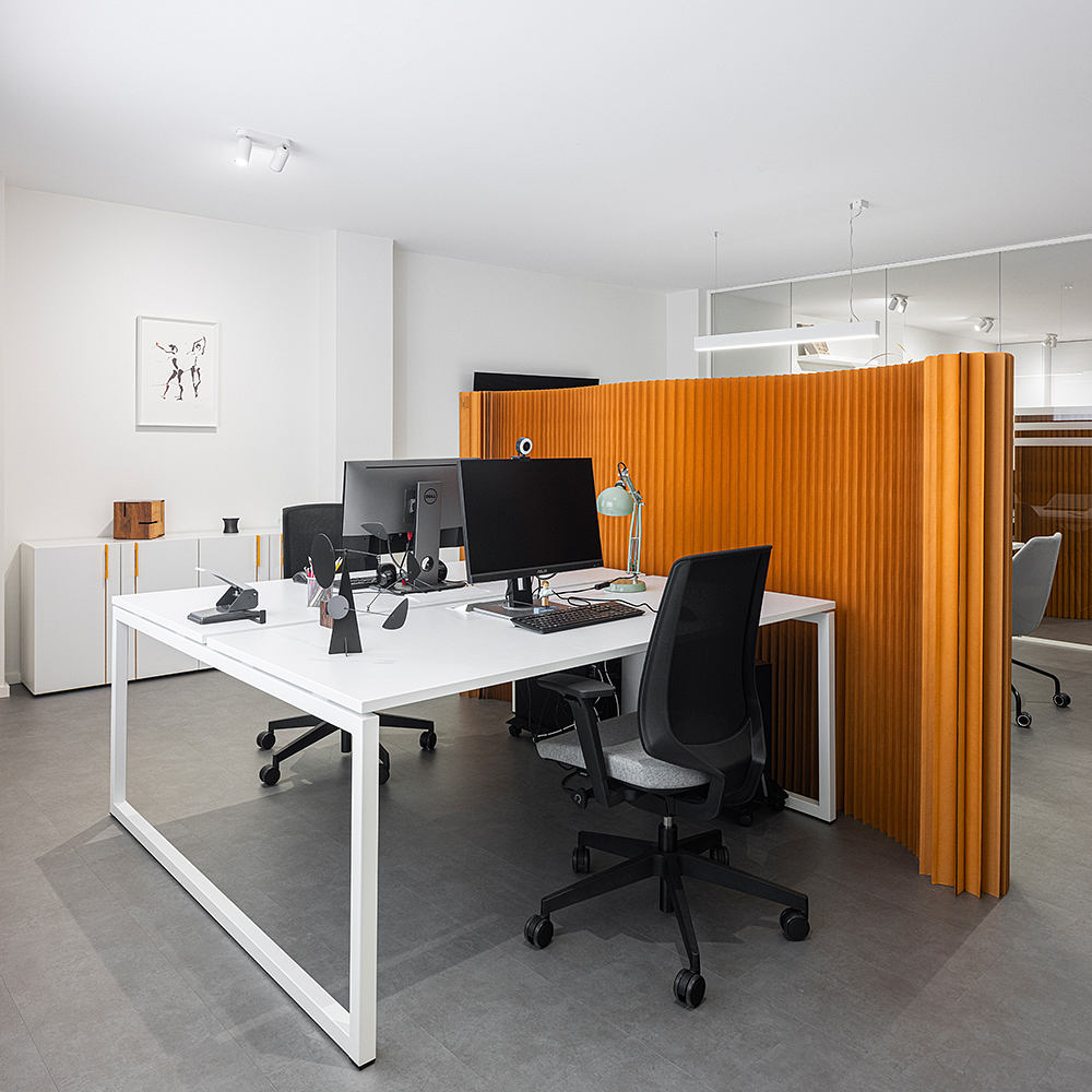 A sleek, modern office space with clean lines, white desks, and vibrant orange partitions.