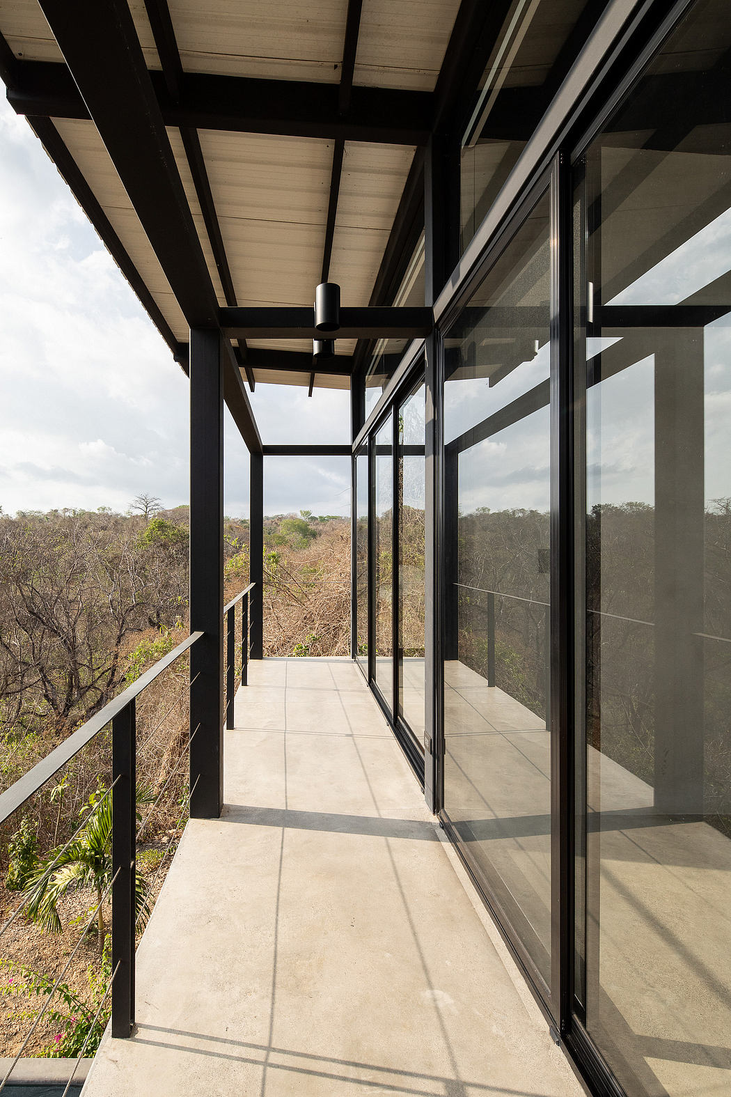 Minimalist hallway with black metal framing, large windows offering scenic views.