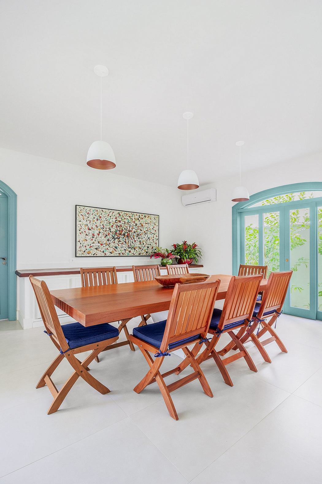 Spacious dining area with wooden furniture, pendant lights, and vibrant artwork.