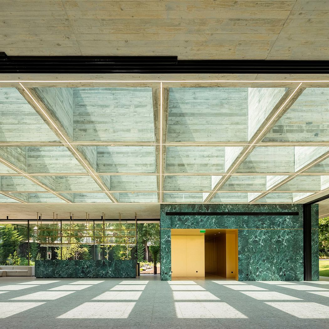 Expansive glass ceiling, geometric patterns, and striking green marble accents create a modern, sophisticated interior.