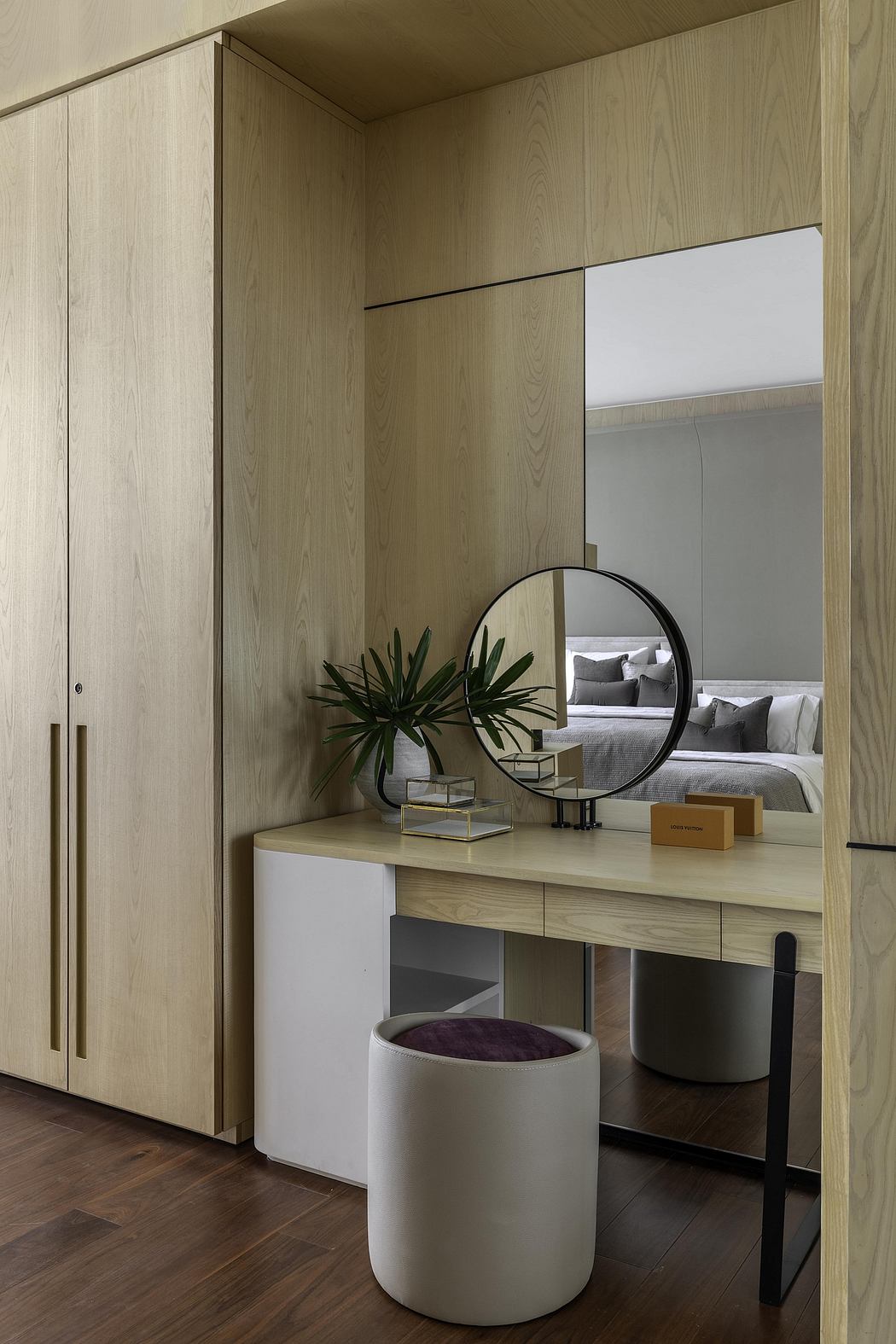 Elegant wooden vanity with round mirror and decorative accents in a cozy bedroom.
