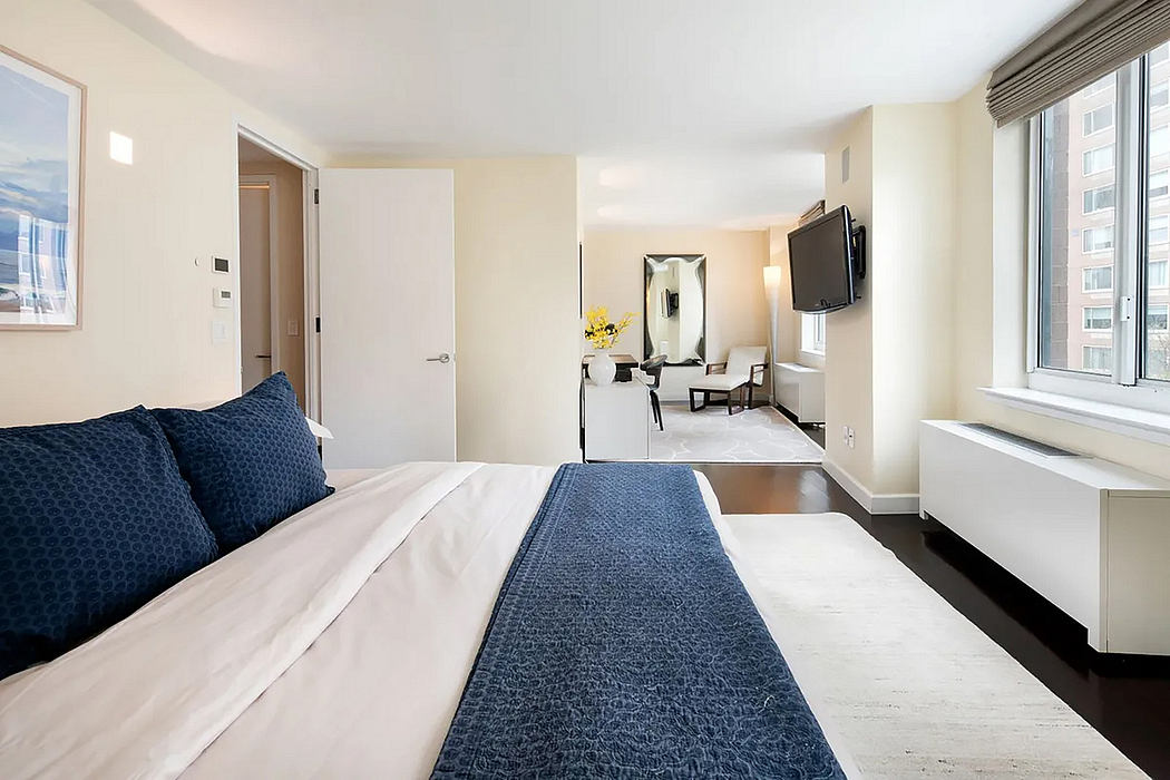 Modern bedroom with clean lines, neutral colors, and large window offering natural light.